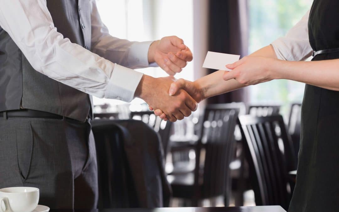 Business people shaking hands after meeting and exchanging business cards.