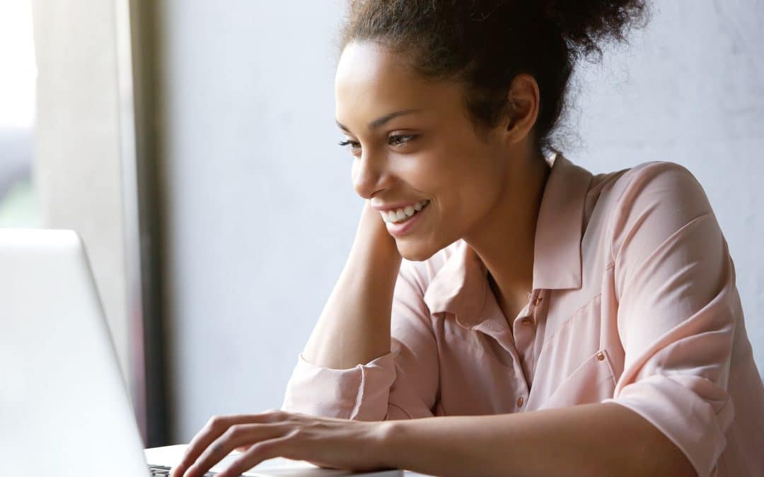 Close up portrait of a beautiful young woman smiling and looking at laptop screen