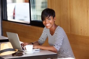 Portrait of a smiling young black woman using laptop