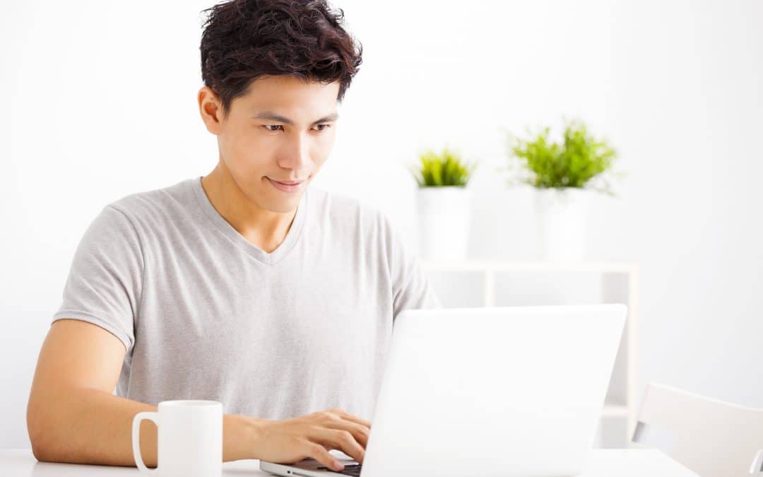 Smiling young man using laptop in living room