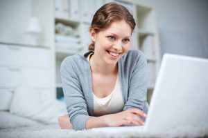A woman smiling at her computer.