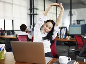 Businesswoman looking at work on laptop computer with satisfaction and stretching arms in the air.