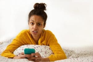 Portrait of a young woman with confused face expression sitting in bed