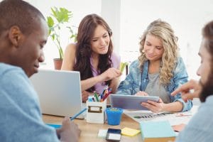 Smiling business people working at desk while using digital tablet in office