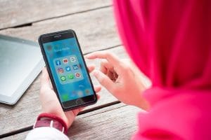 Woman looking at phone and choosing which social media app to click.