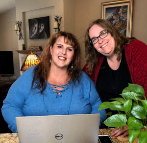 Erika and Emily from Three Girls Media in front of a computer.