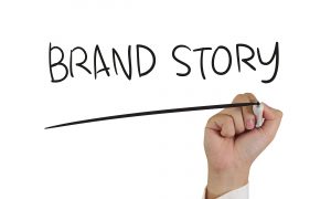 A hand writing the word brand story.