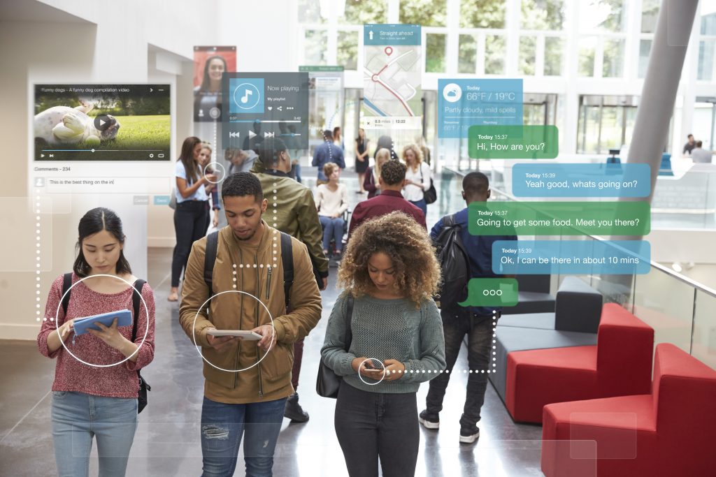 A group of young adults in a hallway looking at the mobile devices