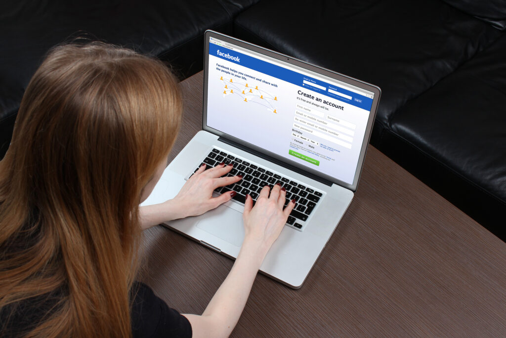 Girl typing on laptop, signing up for a Facebook Page