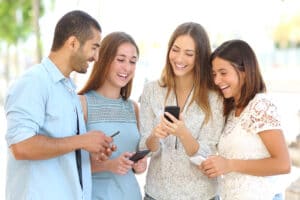 Four young adults using social media on mobile devices