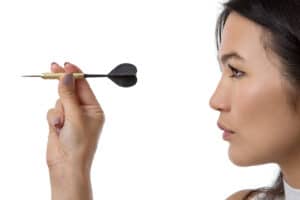 side profile close up shot of woman throwing a dart and taking aim