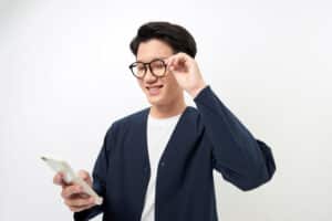 Smiling Asian man looking at a business blog on his phone.