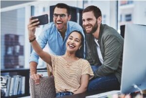 Three people pose for a selfie taken with a smartphone. 