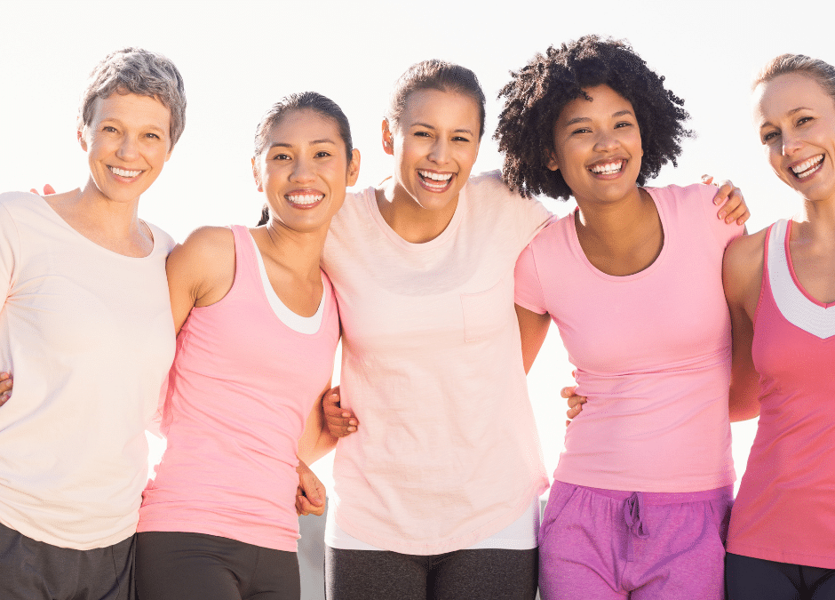 Group of smiling women posing for breast cancer fundraiser.