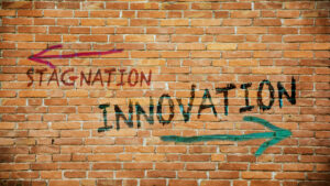 Two arrows on a plain background. The first arrow, smaller and pointing left, labeled 'Stagnation.' The second arrow, larger and pointing right, labeled 'Innovation.'